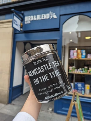 A person holding a tin of tea outside the Newcastle branch of Bird & Blend