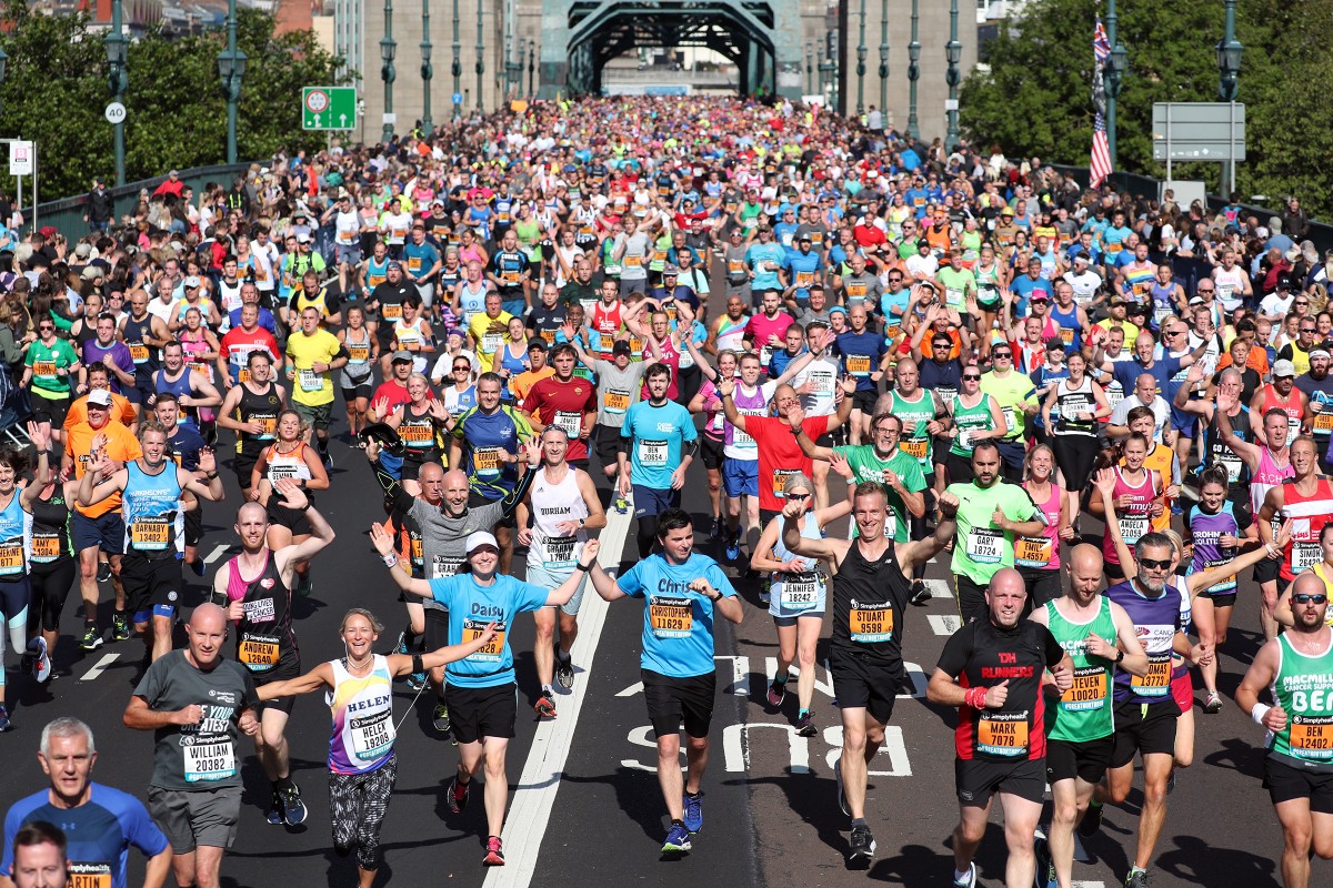 A large group of people running across the Tyne Bridge during the Great North Run half marathon